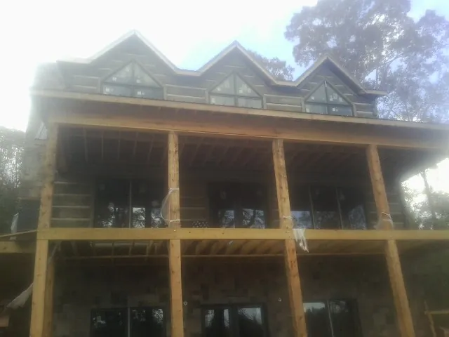Dormers and porch framing on a large log home under construction — Roof Coating work by our crew in Dillsboro
