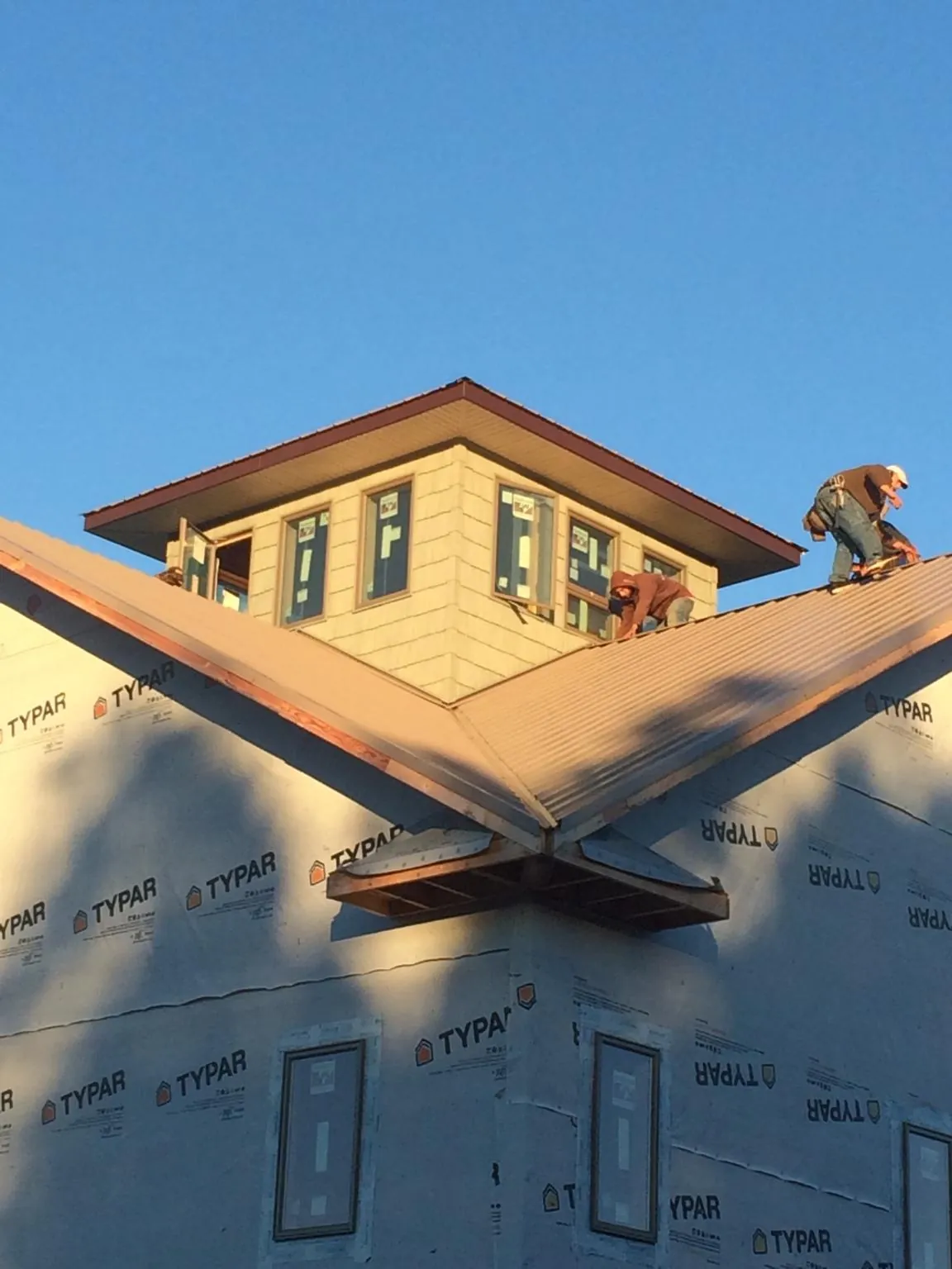 Roofers working around a rooftop cupola on a new metal roof at sunset — Roof Waterproofing in Dillsboro by Roofing Brothers